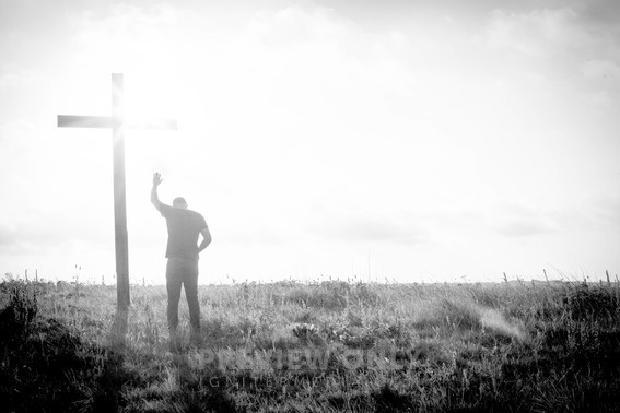 A Man Praying In Front Of A Cross With Raised Hand - Stock Photos | Pearl