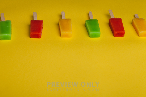 Brightly Colored Popsicles Lined Up On A Yellow Background. - Stock ...