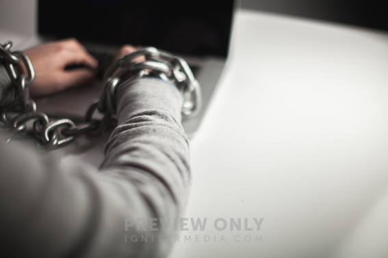 Wrists Bound With Chains Working On Laptop Computer. - Stock Photos | Pearl