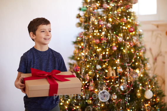 Young Boy Giving A Christmas Gift - Stock Photos | Prixel Creative