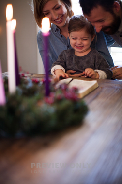 A Family Reading A Bible Near An Advent Wreath - Stock Photos | Pearl